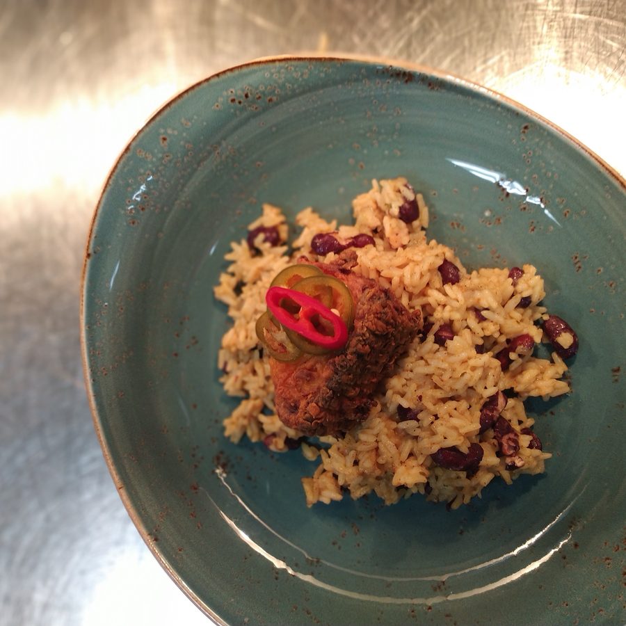 Fried fish over red beans and rice with sliced chiles